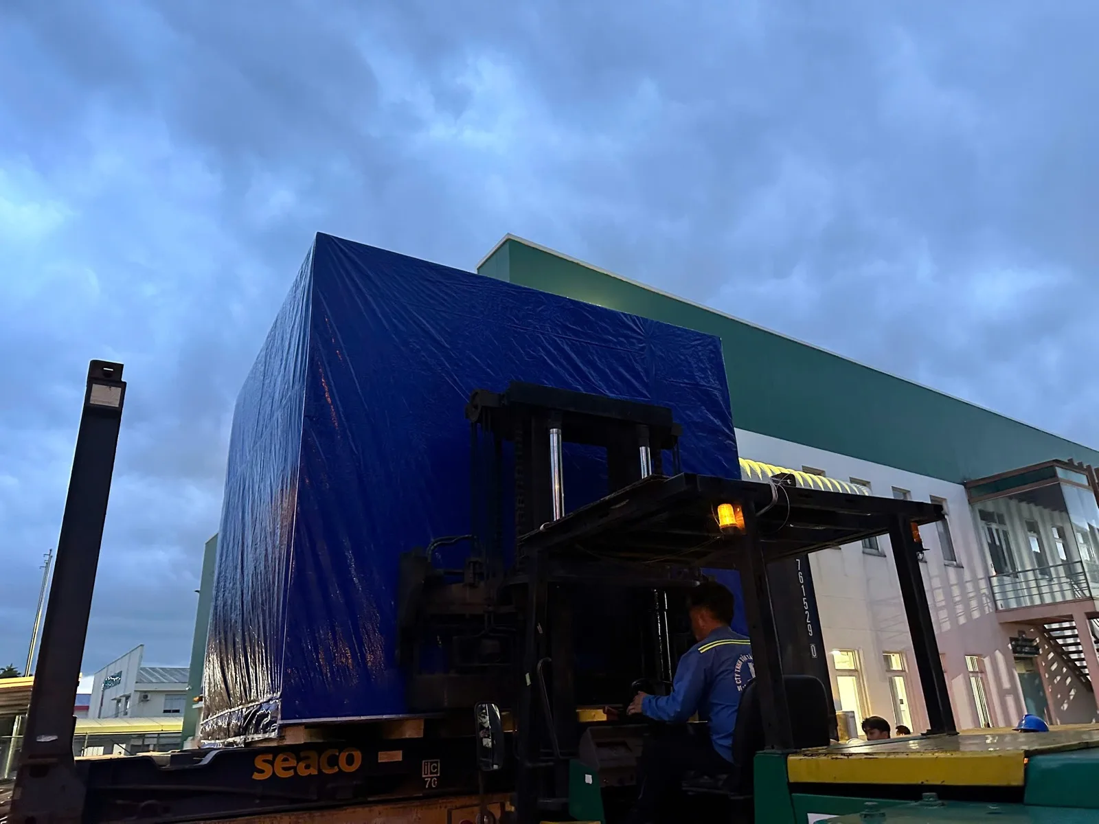 Forklift loading a protected machinery crate into a container